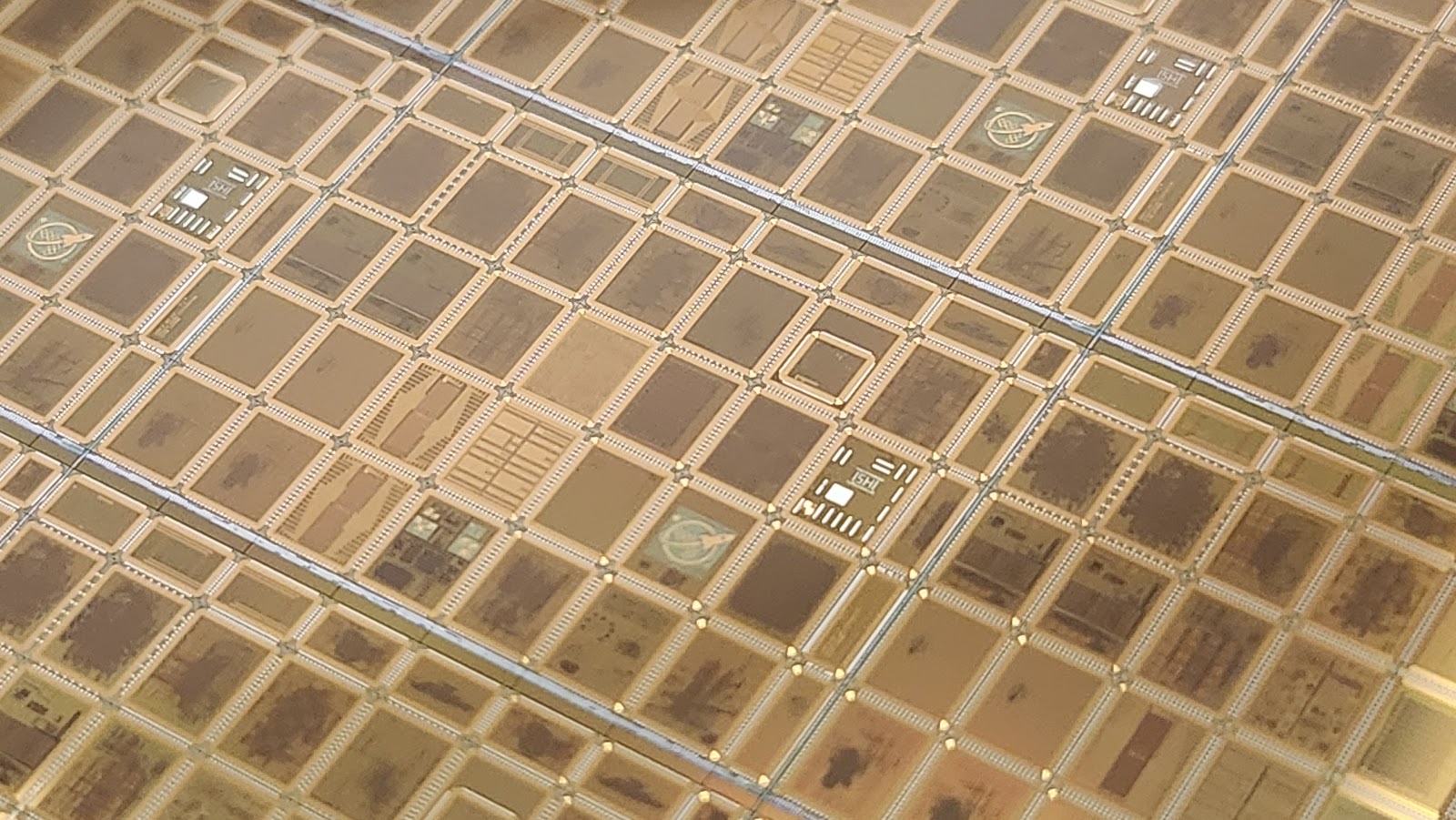 Macro photo of a GF180MCU multi-project wafer: a gold grid of dies